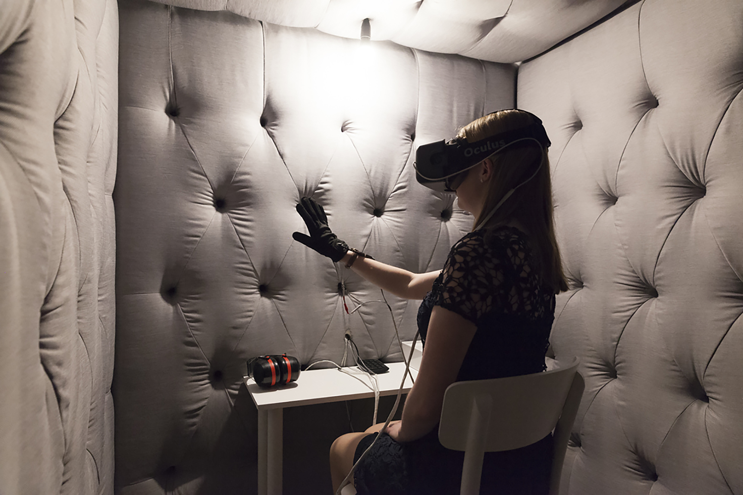 ​​​​​​​A person surrounded by padded walls wearing a headset over their eyes with a glove on their hand