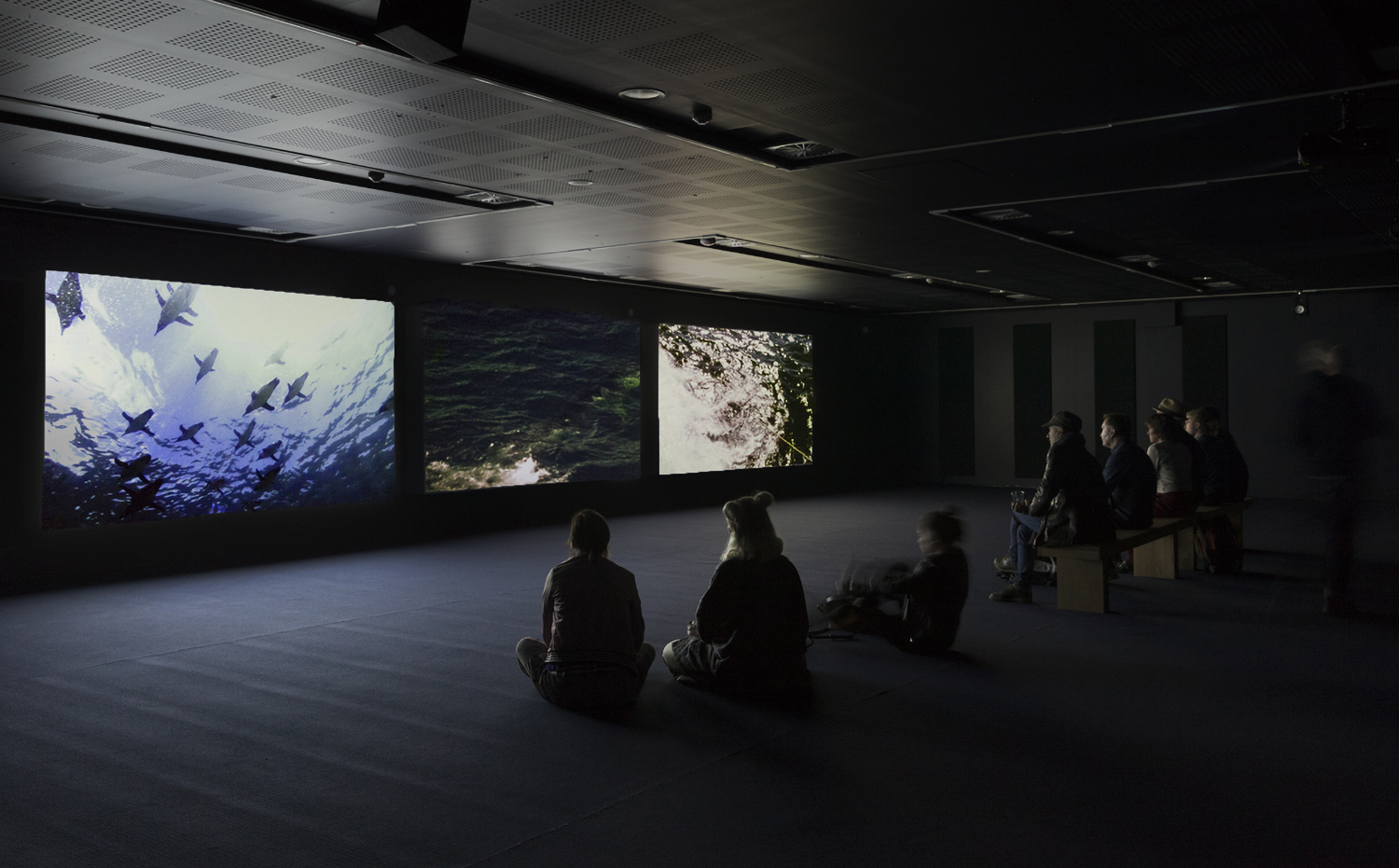 A group of people sitting on the floor watching a video 