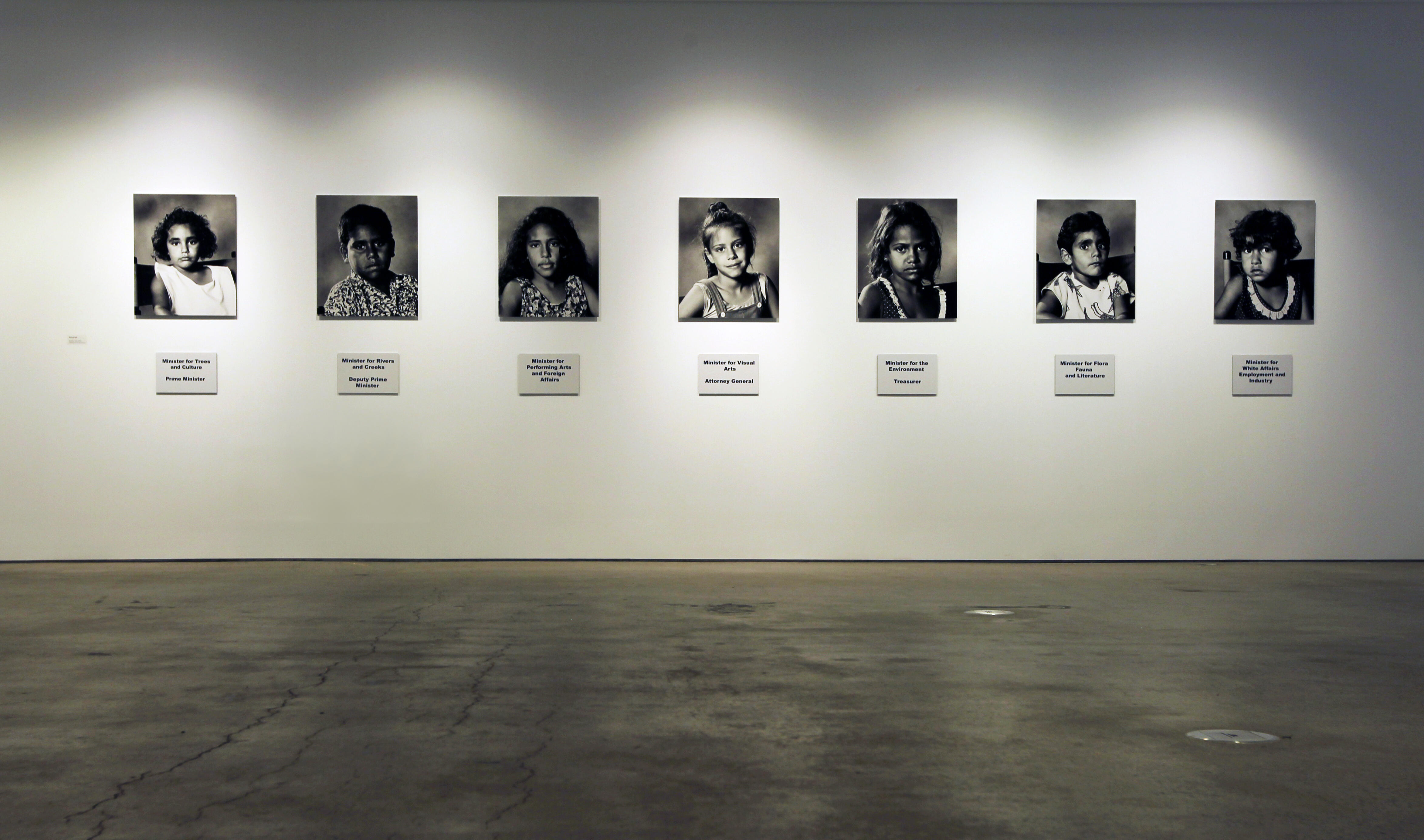 Installation view of seven photographs mounted onto a white gallery wall.