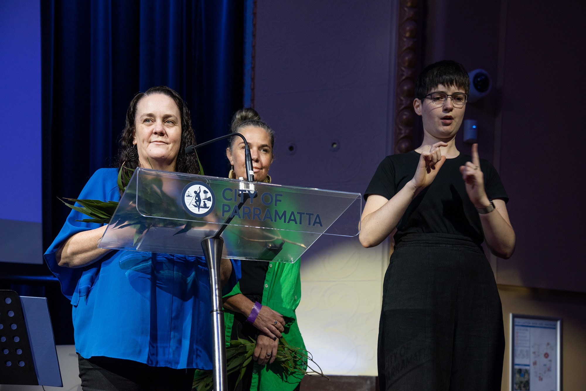 Linda Sainsbury stand at a City of Parramatta lectern with a sign language interpreter.