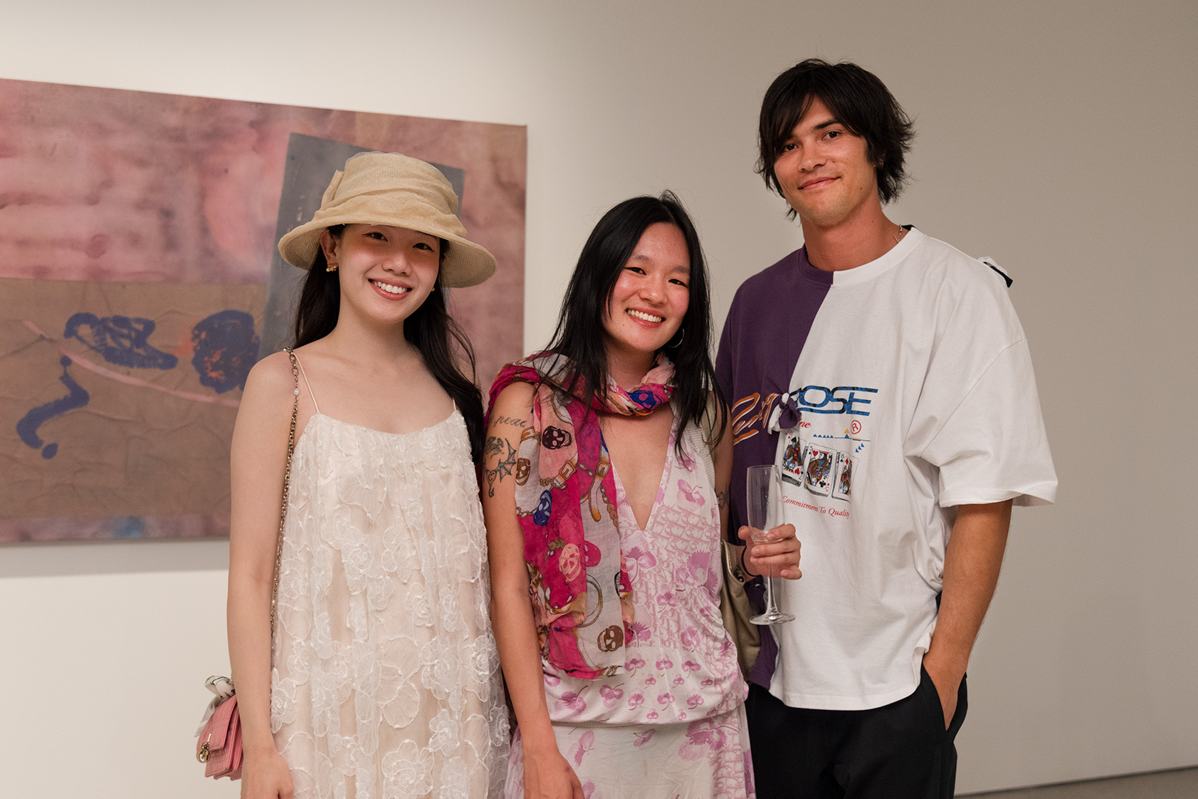 Artist Remy Faint and two people stand in front of a abstract artwork during an exhibition opening.