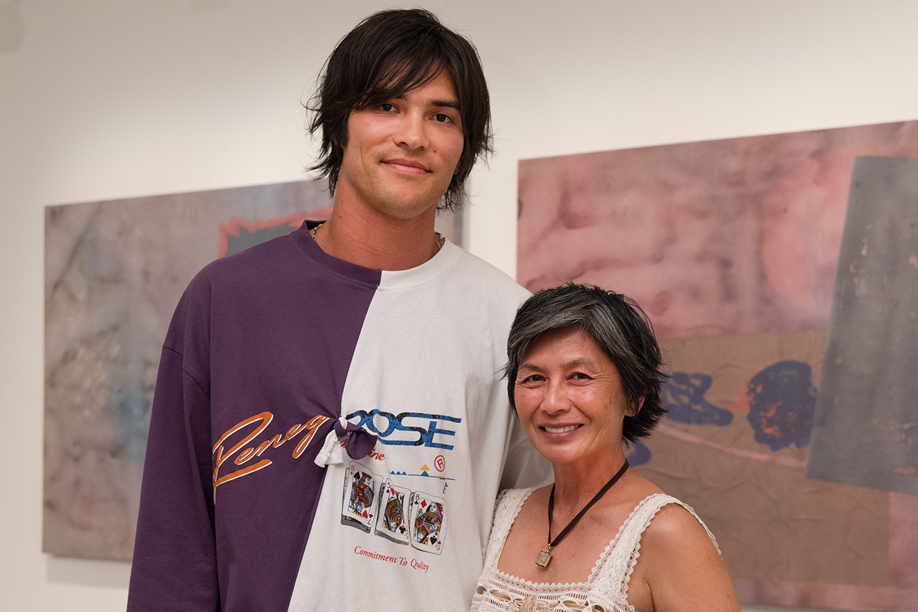 Artist Remy Faint and family pose together in front of large abstract paintings displayed on a gallery wall.