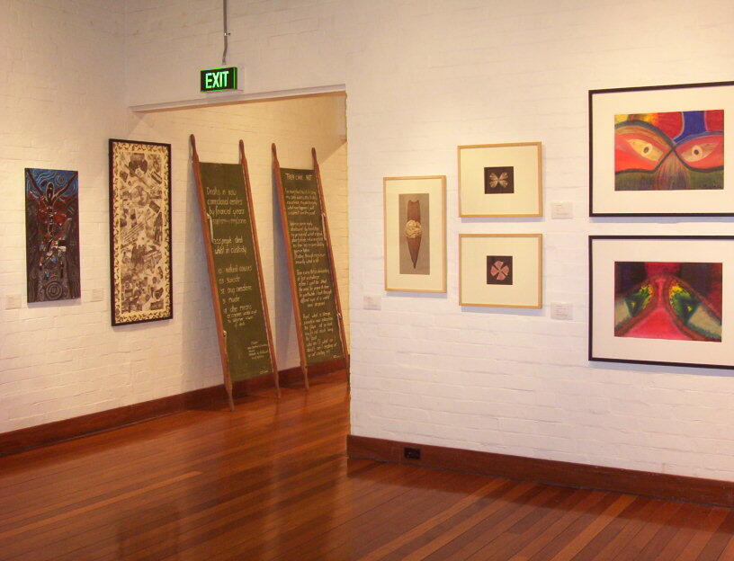 White-walled exhibition space featuring various framed paintings