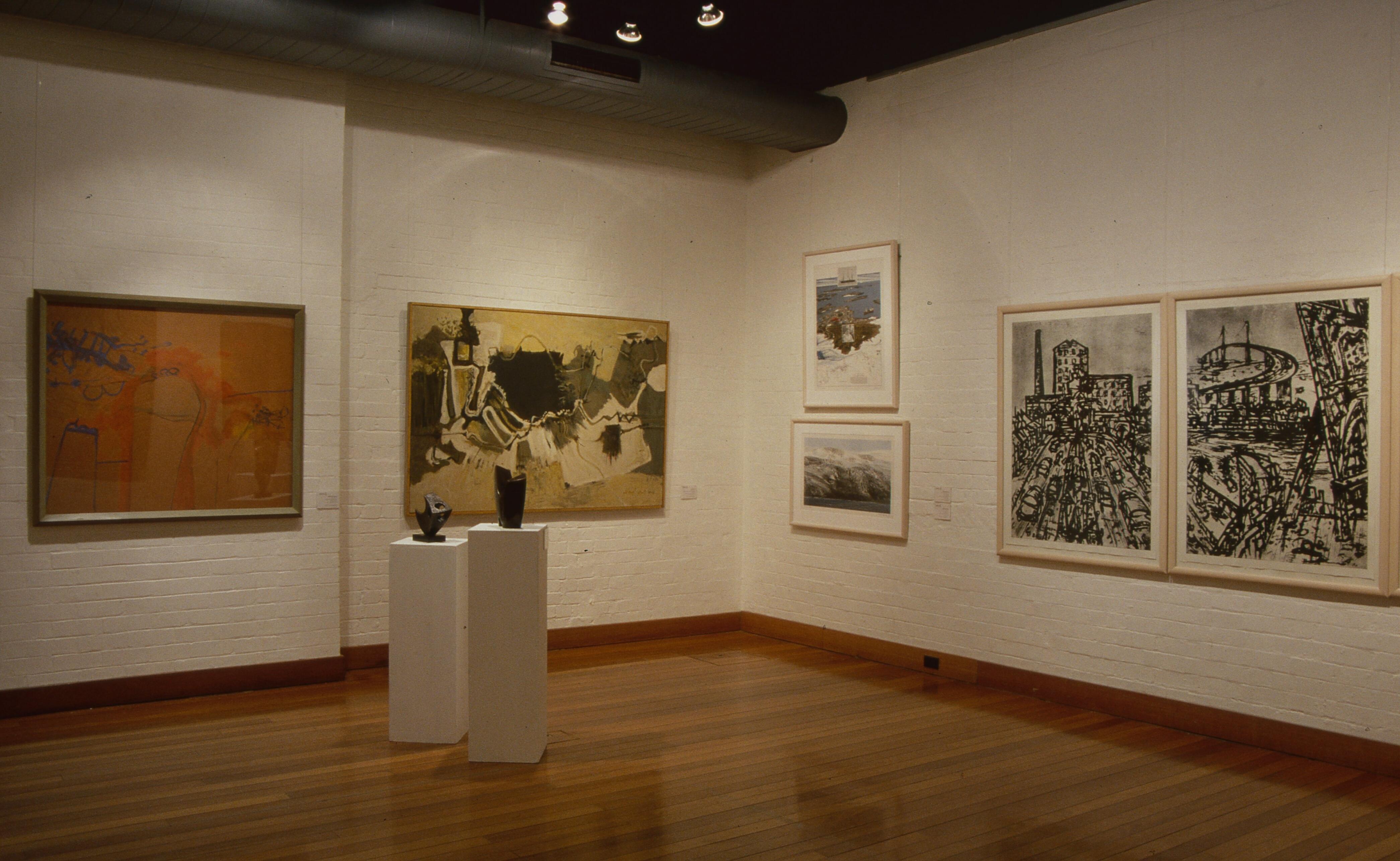 Art gallery corner featuring abstract paintings, framed prints, and two small sculptures displayed on pedestals.