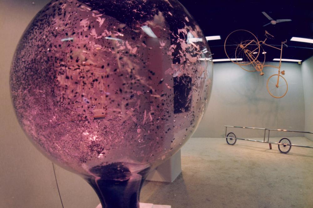 Installation view of gallery showing a circular glass object close up 